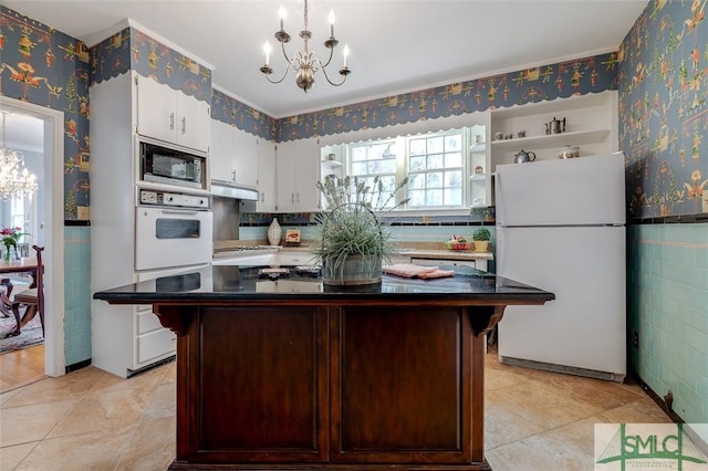 kitchen with dark countertops, wallpapered walls, a chandelier, white appliances, and open shelves