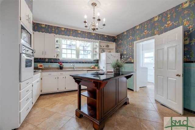 kitchen with open shelves, a sink, white appliances, white cabinets, and wallpapered walls