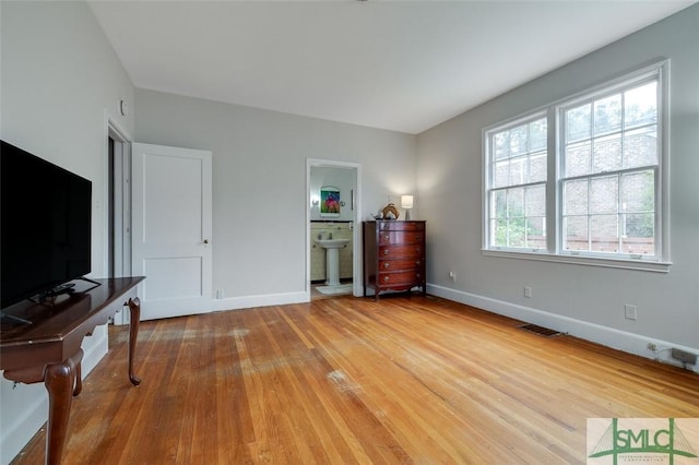 bedroom with wood finished floors, visible vents, ensuite bathroom, and baseboards