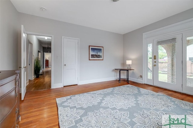 unfurnished room featuring baseboards, attic access, and light wood finished floors