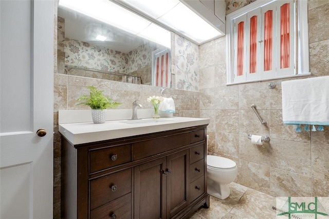 bathroom with toilet, tile walls, and vanity