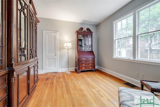 living area with visible vents, light wood-style flooring, baseboards, and a healthy amount of sunlight