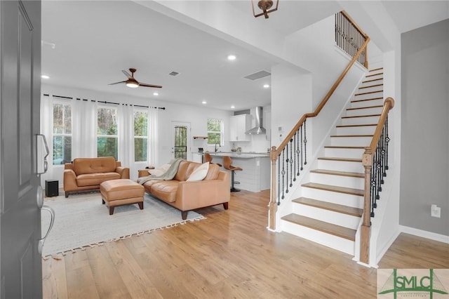 living room with light wood-style floors, visible vents, and a wealth of natural light