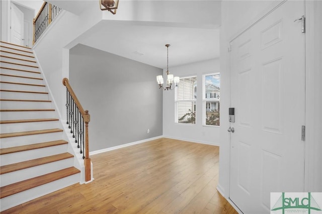 entrance foyer with stairs, an inviting chandelier, light wood-style flooring, and baseboards