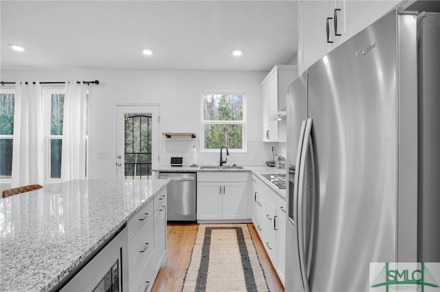 kitchen featuring a sink, stainless steel appliances, white cabinets, and light wood finished floors