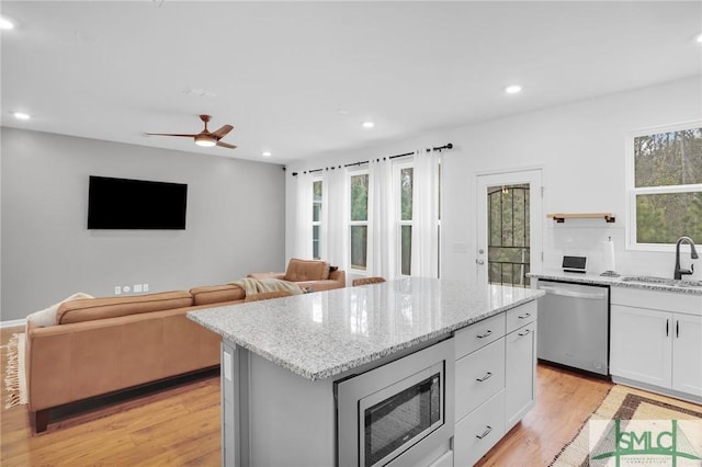 kitchen with light wood-style flooring, white cabinets, appliances with stainless steel finishes, and a sink