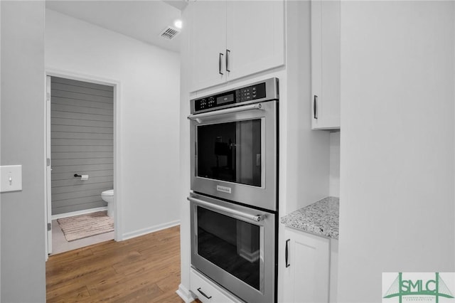 kitchen featuring white cabinetry, double oven, visible vents, and light wood-type flooring