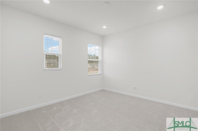 spare room featuring recessed lighting, light colored carpet, and baseboards