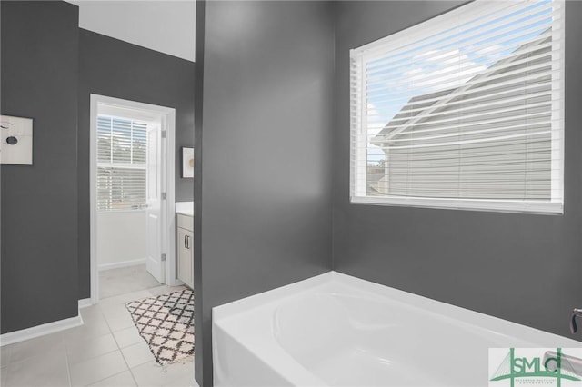 bathroom with tile patterned floors, a bath, a healthy amount of sunlight, and baseboards