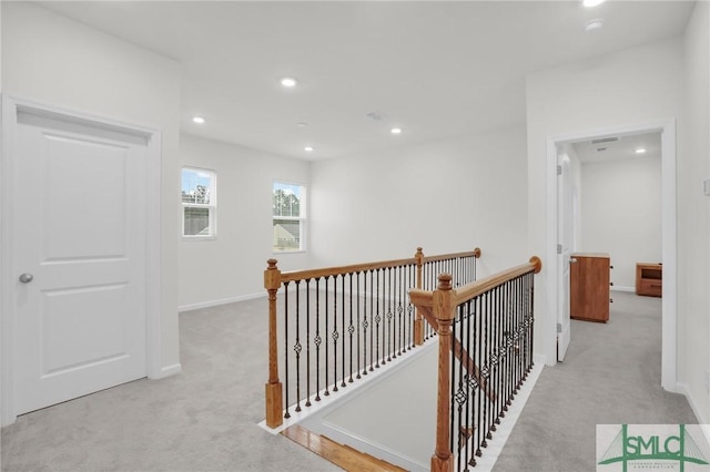 hallway featuring recessed lighting, baseboards, an upstairs landing, and light colored carpet