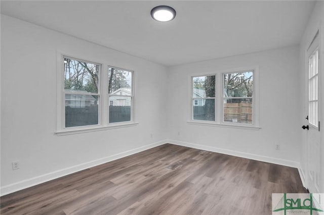 empty room with wood finished floors, baseboards, and a wealth of natural light