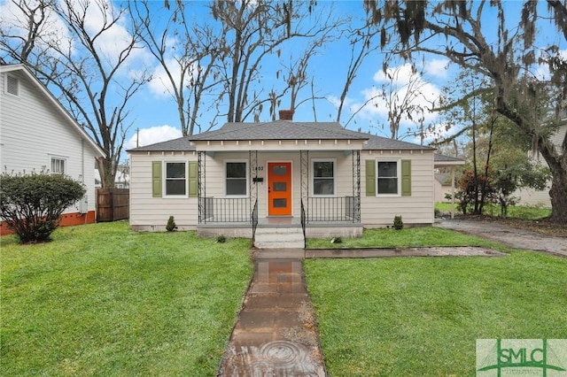 bungalow-style home featuring a front lawn, fence, covered porch, and a chimney