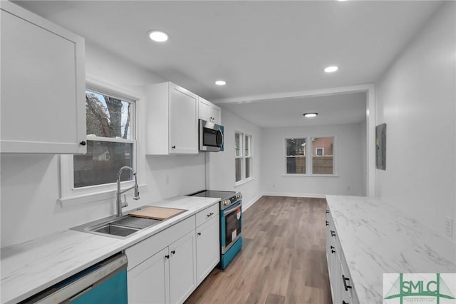 kitchen featuring light wood-type flooring, a sink, recessed lighting, stainless steel appliances, and white cabinets