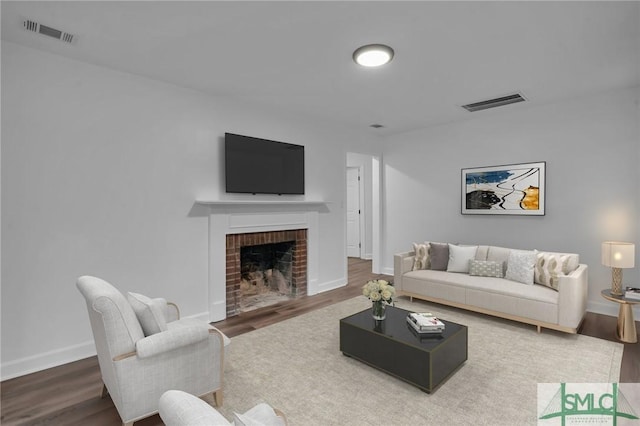 living room with visible vents, baseboards, wood finished floors, and a fireplace