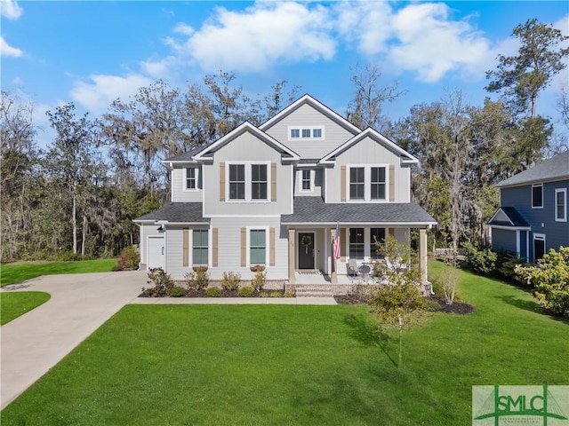 traditional-style home featuring concrete driveway, a garage, covered porch, and a front lawn