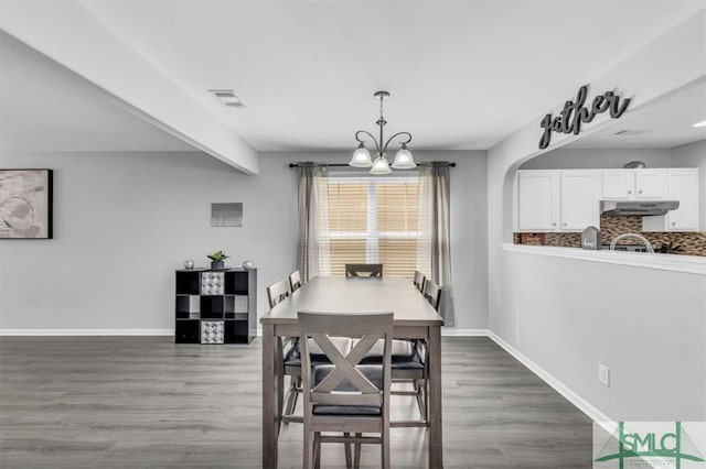 dining room with beamed ceiling, baseboards, wood finished floors, and a chandelier