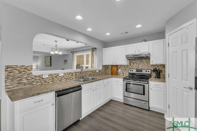 kitchen featuring under cabinet range hood, a sink, wood finished floors, appliances with stainless steel finishes, and white cabinets