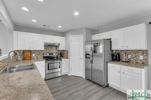 kitchen with a sink, stainless steel appliances, white cabinets, light wood-style floors, and under cabinet range hood