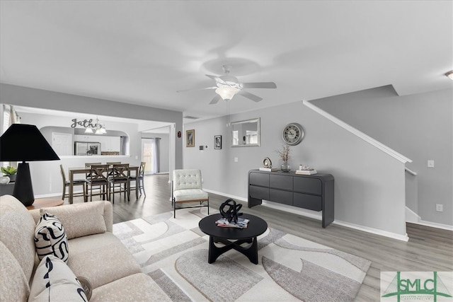 living room featuring wood finished floors, baseboards, and ceiling fan