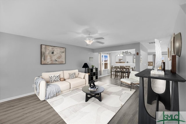 living area with ceiling fan, baseboards, and wood finished floors