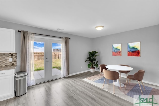 dining area with french doors, baseboards, visible vents, and light wood-style flooring