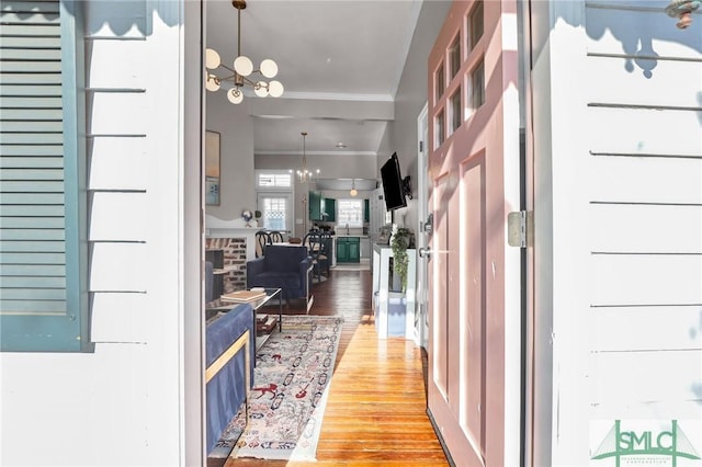 entrance foyer with wood finished floors, an inviting chandelier, and ornamental molding