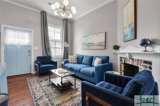 living room featuring wood finished floors, a notable chandelier, ornamental molding, and a fireplace