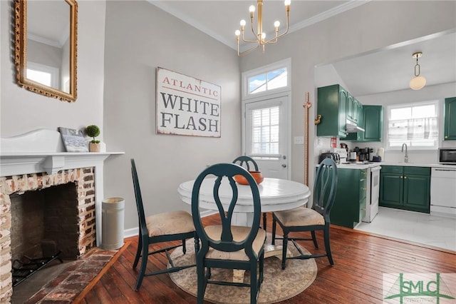 dining room with ornamental molding, a brick fireplace, an inviting chandelier, and hardwood / wood-style floors