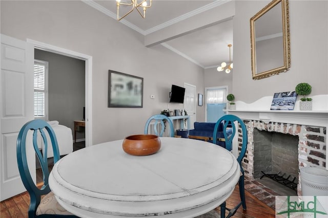 dining space featuring a chandelier, ornamental molding, a fireplace, and wood finished floors