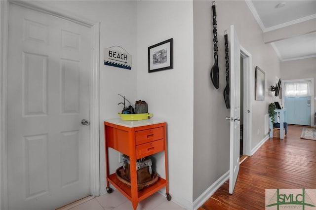 hallway featuring baseboards, ornamental molding, and light wood finished floors