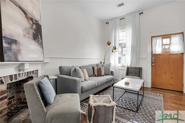 living area with visible vents, a wainscoted wall, wood finished floors, and a fireplace