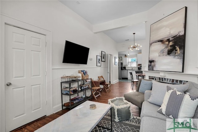 living room featuring beam ceiling, baseboards, an inviting chandelier, and wood finished floors