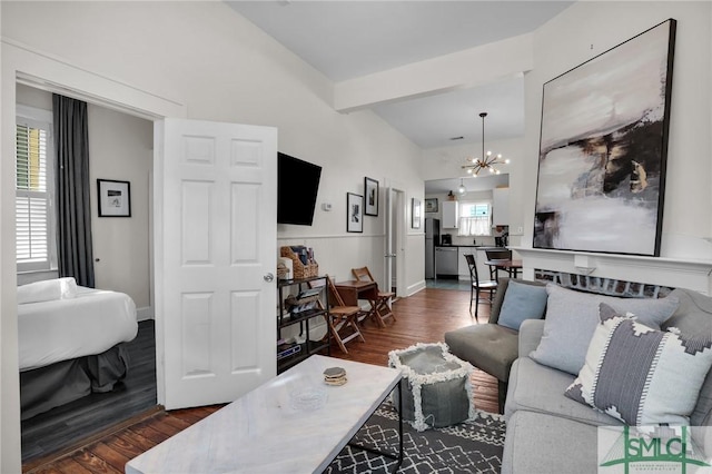 living area featuring dark wood-style floors, a chandelier, baseboards, and beam ceiling