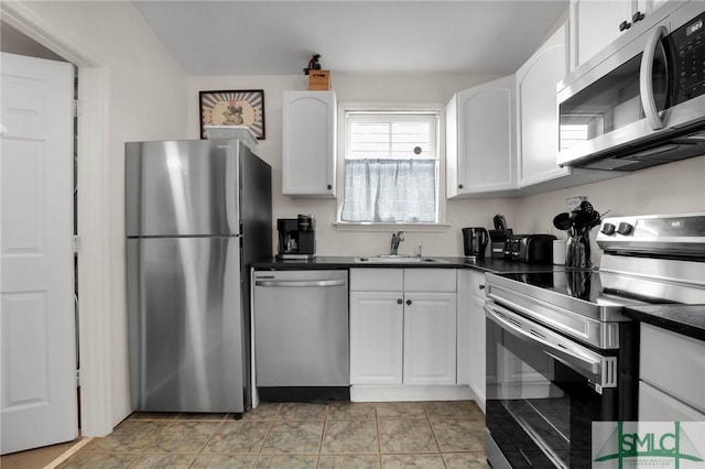 kitchen featuring dark countertops, white cabinets, stainless steel appliances, and a sink