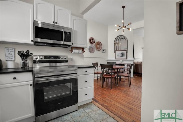 kitchen featuring light wood-style flooring, dark countertops, appliances with stainless steel finishes, and white cabinets