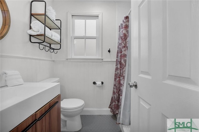 full bathroom with a wainscoted wall, toilet, vanity, and a shower with curtain