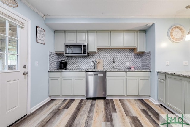 kitchen with a sink, stainless steel appliances, light wood-type flooring, and crown molding