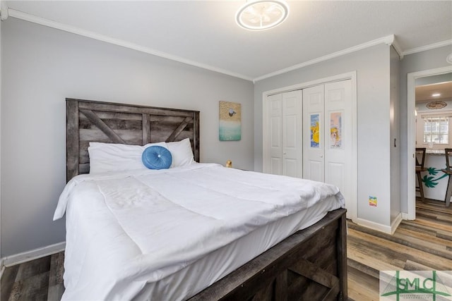 bedroom with a closet, crown molding, baseboards, and wood finished floors