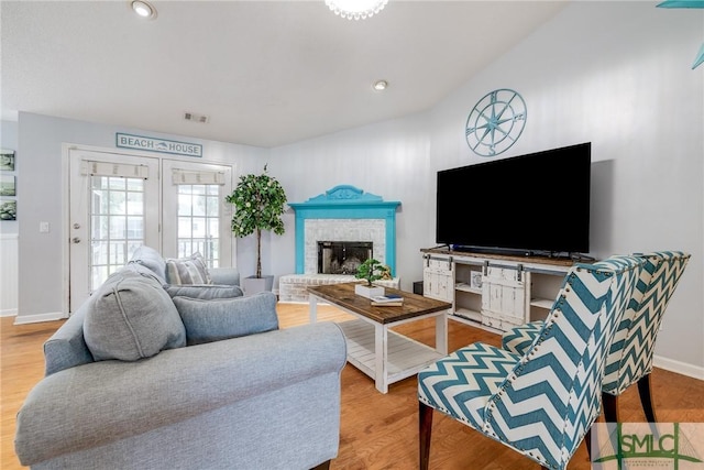 living area with wood finished floors, visible vents, baseboards, recessed lighting, and a brick fireplace