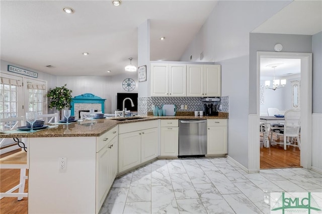 kitchen featuring marble finish floor, dishwasher, a peninsula, and a sink