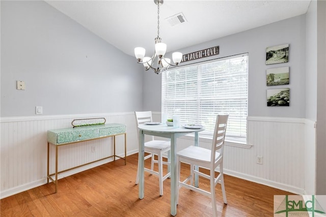 dining room featuring visible vents, wood finished floors, a notable chandelier, and a wainscoted wall