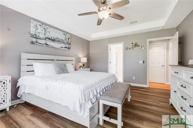 bedroom featuring visible vents, a raised ceiling, dark wood-type flooring, and baseboards