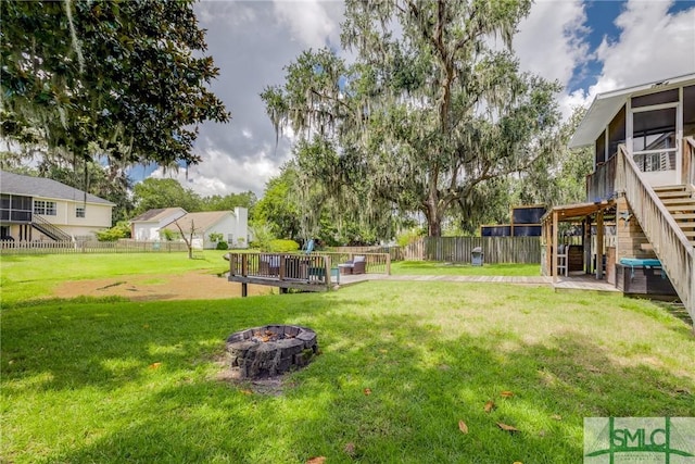 view of yard featuring stairway, a wooden deck, a fenced backyard, a sunroom, and a fire pit