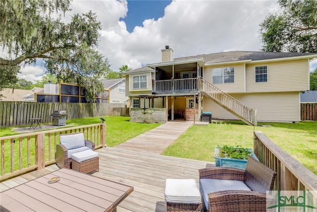 back of property with stairway, a wooden deck, a fenced backyard, a chimney, and a lawn