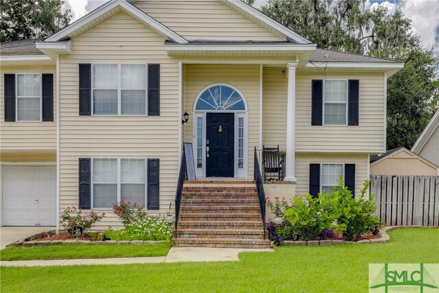 bi-level home with a front lawn, fence, a garage, and driveway