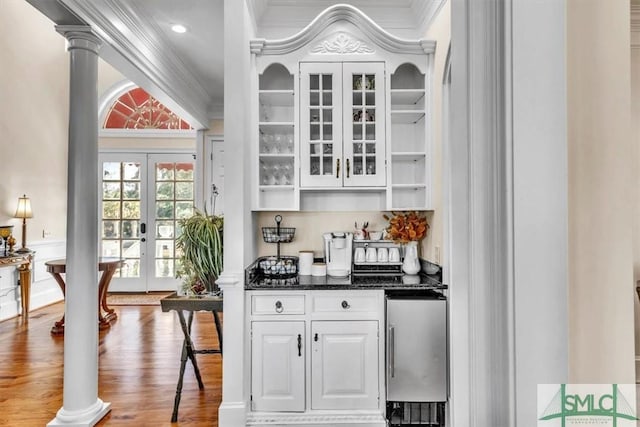 bar featuring decorative columns, wood finished floors, crown molding, and french doors