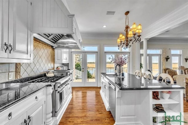 kitchen with a sink, french doors, stainless steel appliances, white cabinets, and crown molding