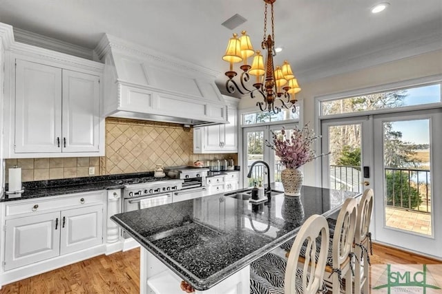 kitchen with a sink, french doors, white cabinets, and crown molding