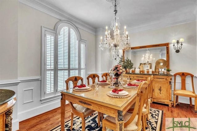 dining room featuring light wood-type flooring, ornamental molding, a notable chandelier, and a healthy amount of sunlight