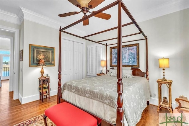 bedroom with baseboards, ornamental molding, a closet, and wood finished floors